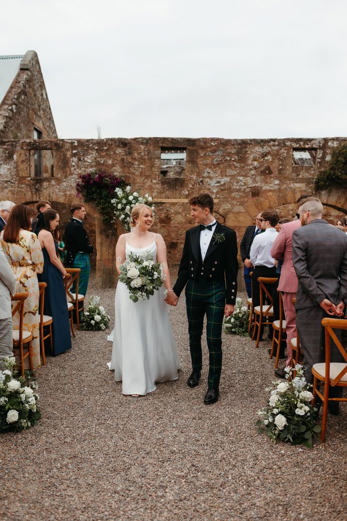 just married- bride + groom walking down aisle