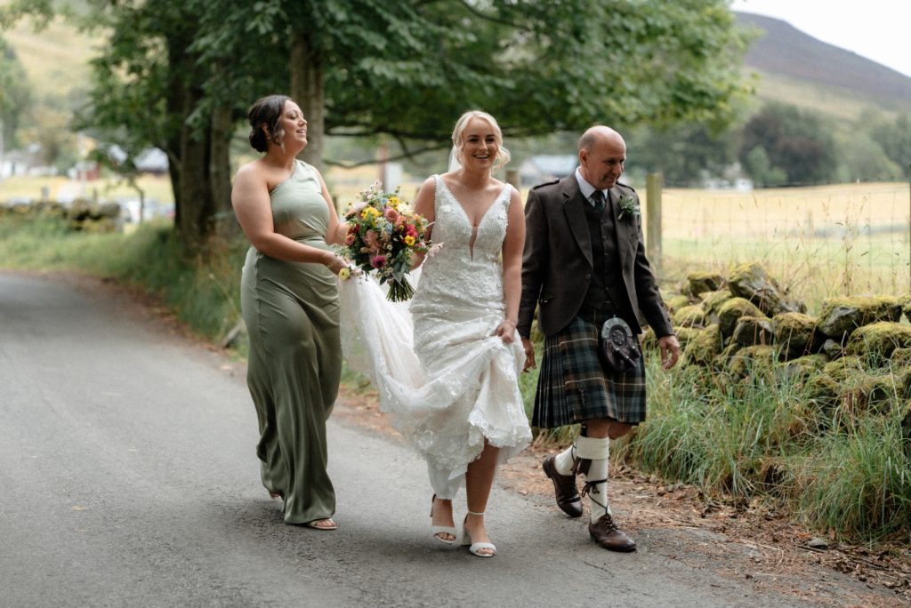 bride carrying bouquet walking to the kirk
