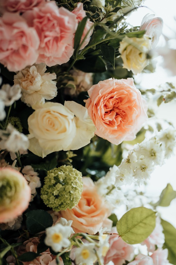 Rossie-on-the-earn-perthshire-wedding-fraoch-floral-design 3 - Fraoch Floral Design Close-up of a pastel bouquet featuring peach and cream roses, white blossoms, and green foliage.