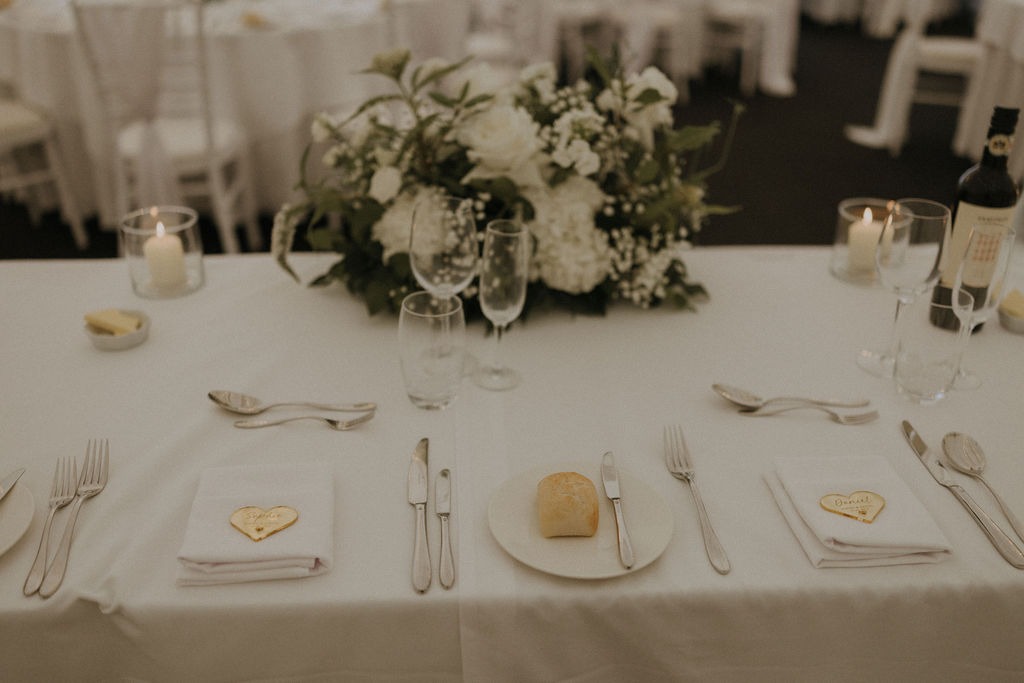 angus-wedding-florist-kinnettles-castle 7 - Fraoch Floral Design Elegant banquet table set with white linens, floral centerpiece, candles, and bread on a plate for two при.