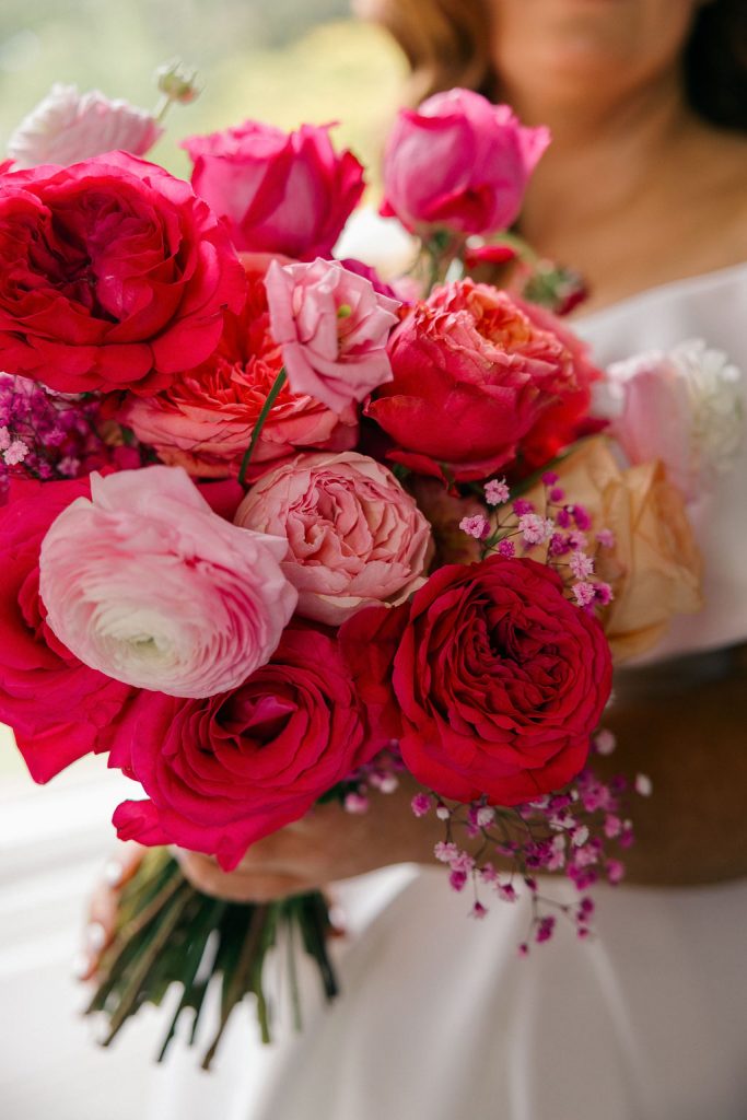 angus-wedding-flowers-florist-fraoch-floral-design 11 - Fraoch Floral Design Close-up of a bride's bouquet featuring pink and red roses with delicate filler flowers like baby's breath