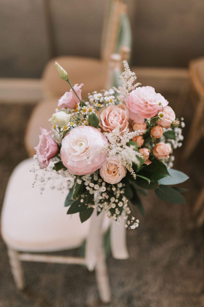 Close-up of a blush pink bouquet with roses, peonies, and white baby's breath (gypsophila) with green foliage.