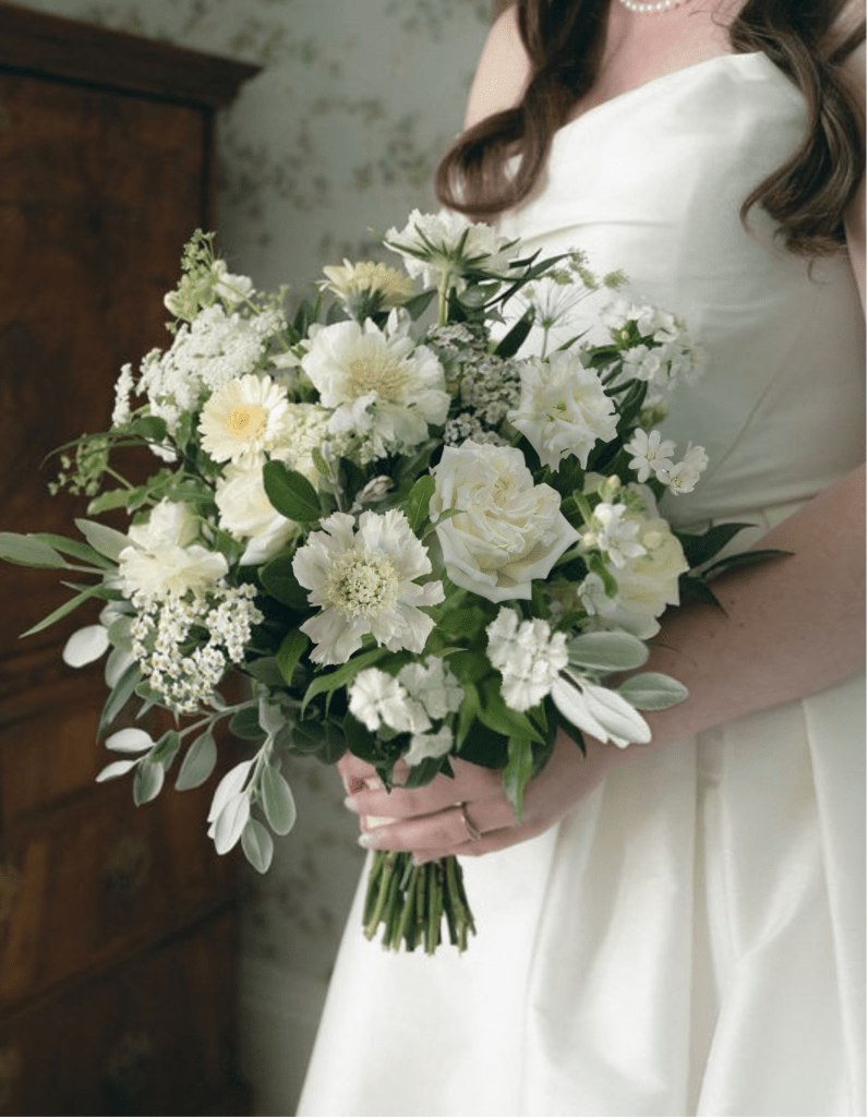 kinblethmont-house-wedding-angus- 3 - Fraoch Floral Design Bride in a white wedding dress holds a large white bouquet with green foliage, close up from the waist up.