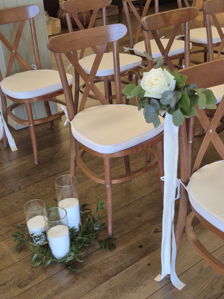 bachilton-barn-wedding-perthshire -20 1 - fraoch floral design fraoch floral design wooden folding chairs with white cushions arranged for a wedding, a cream rose bouquet with greenery tied to a chair.